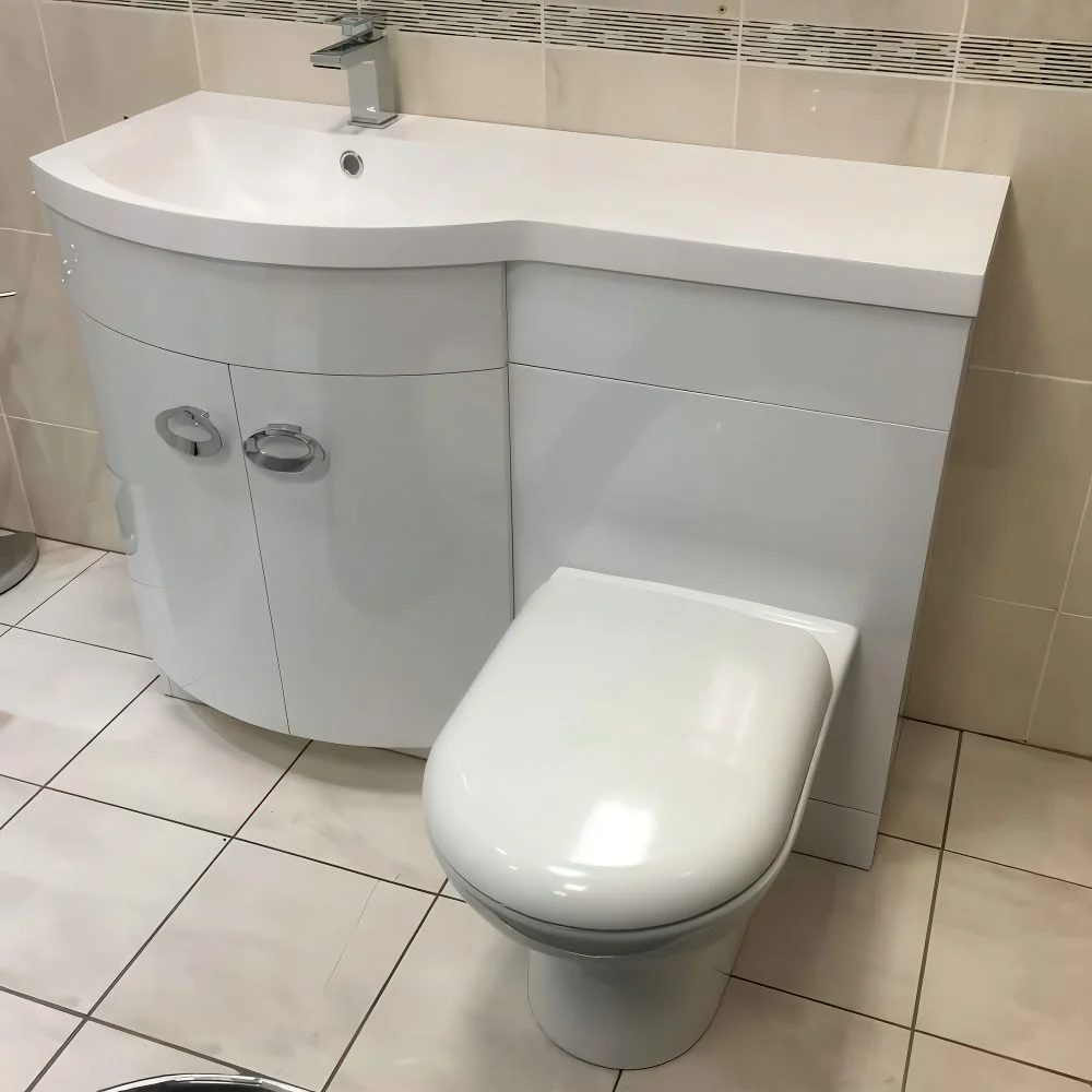 Kavisli lavabo ve tezgah üzerine yerleştirilmiş tuvalet.