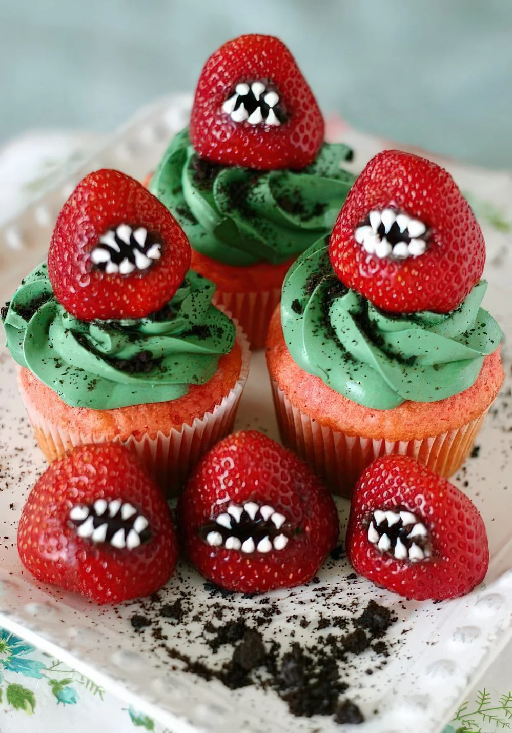 Parlak ve korkutucu Cadılar Bayramı cupcakeleri, yeşil süslemeler ve dişli kırmızı çileklerle harika görünür.