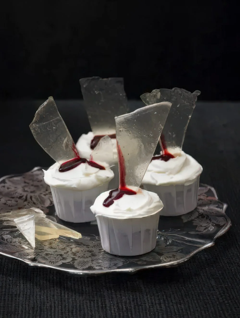 Kanlı cam parçalarıyla süslenmiş şık beyaz cupcakeler, Dexter temalı olsun olmasın her Cadılar Bayramı partisinde zarif durur.