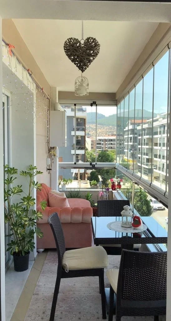 Bu dar alan, manzaralı dış mekan yemek odası, bitkiler ve mercan renkli bir kanepe içeriyor.
