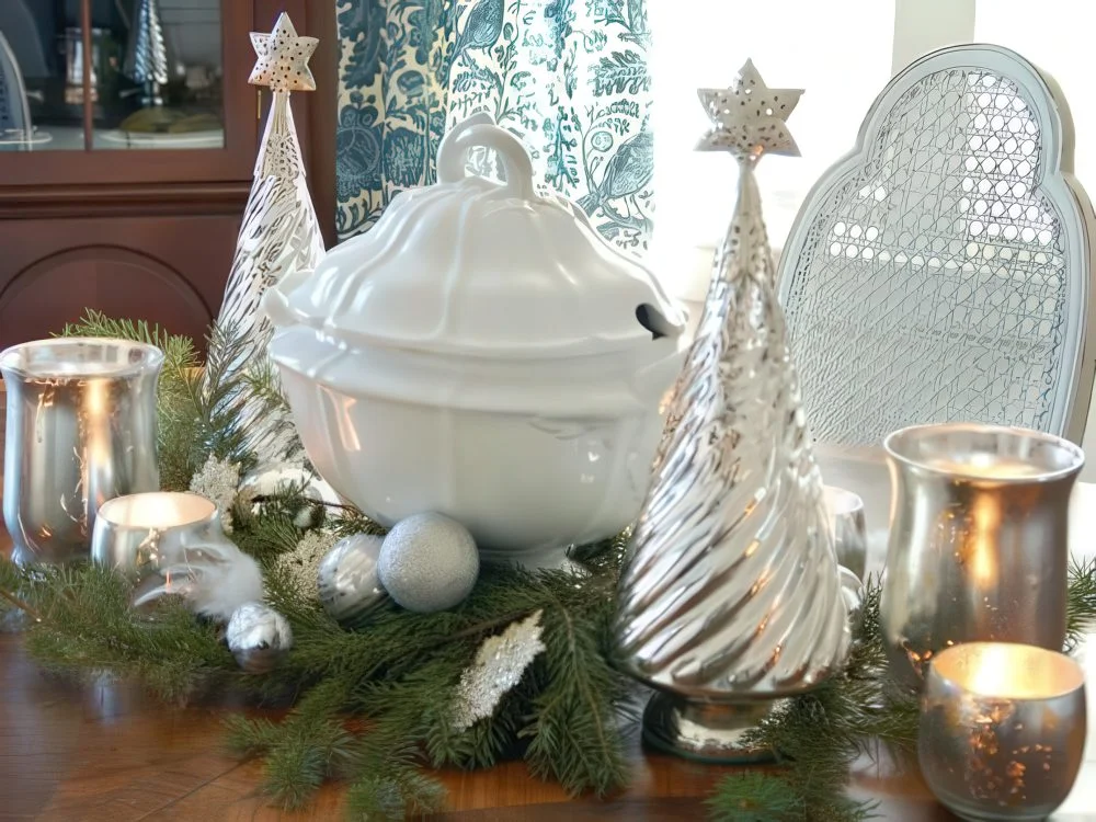 Cıva camdan ağaçlar, mumluklar, gümüş süslerle tamamlanmış yeşilliklerden oluşan şık ve parlak gümüş bir Noel masa ortası.
