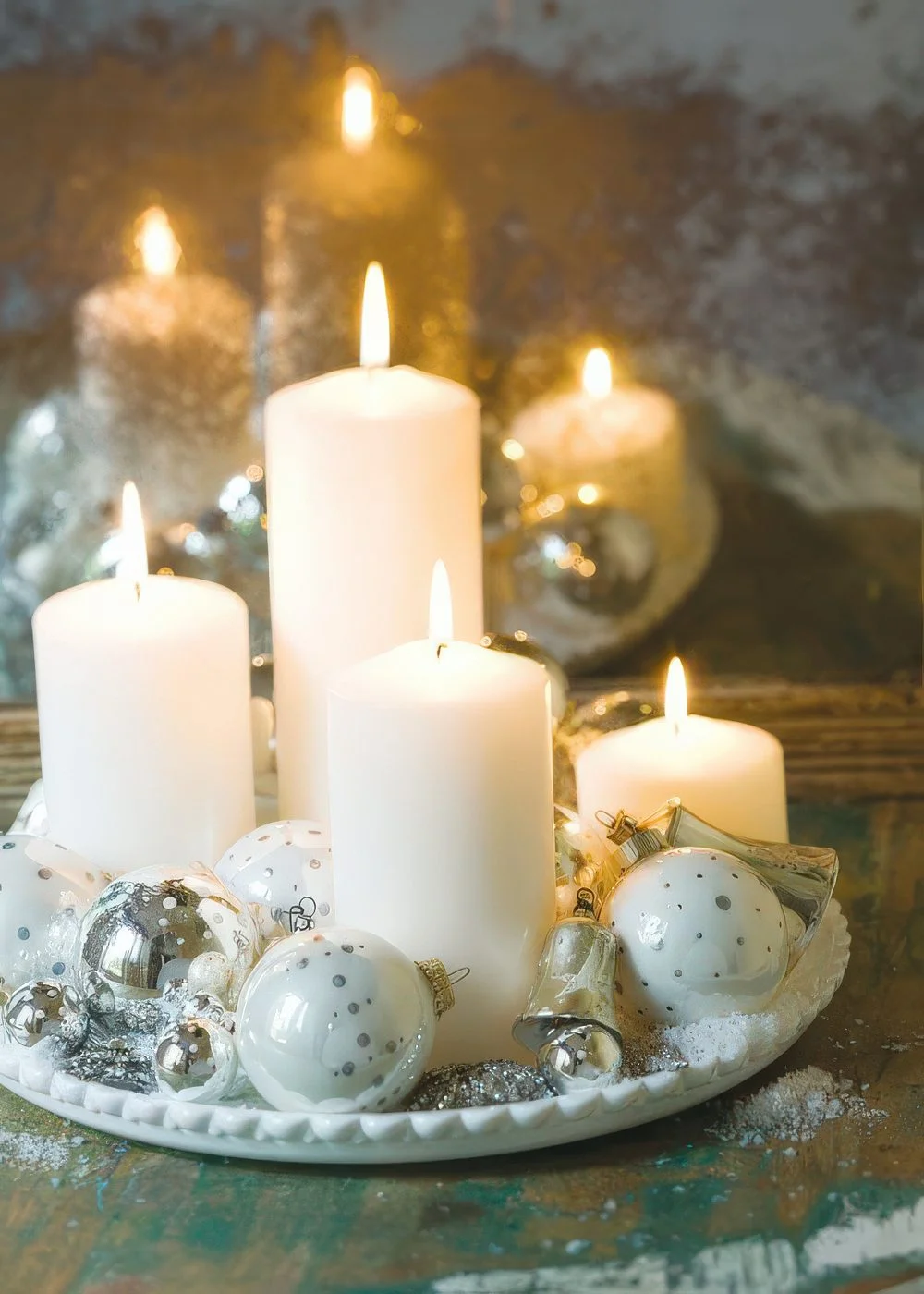 Beyaz tepside beyaz ve gümüş Noel süsleri, sütun mumlar ve yapay kar harika bir merkez.
