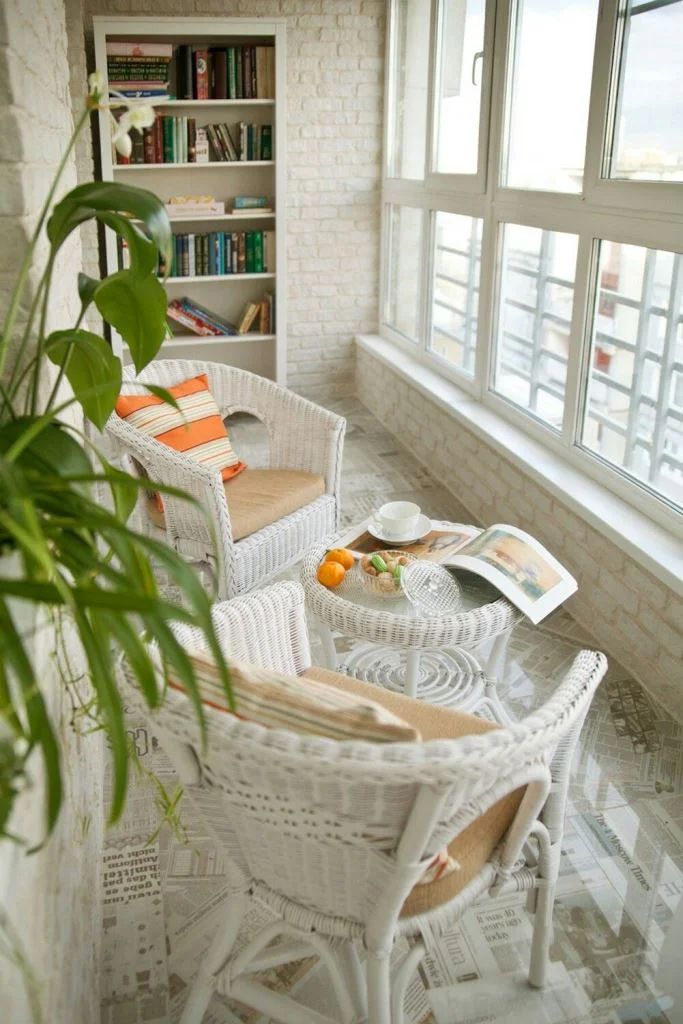 Beyaz balkon, seçilen renklerle ferah ve geniş hissediliyor, sahte tuğla dokusu ekliyor. Beyaz hasır mobilyalar dış mekân hissi katıyor.