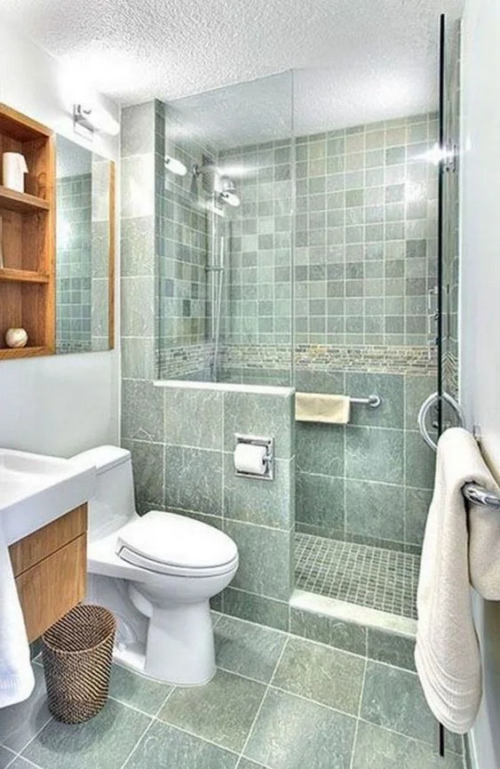 Canlı yeşil banyo, küçük duş alanı, lekeli lavabo, raf ünitesi, beyaz cihazlar ve beyaz tekstiller.