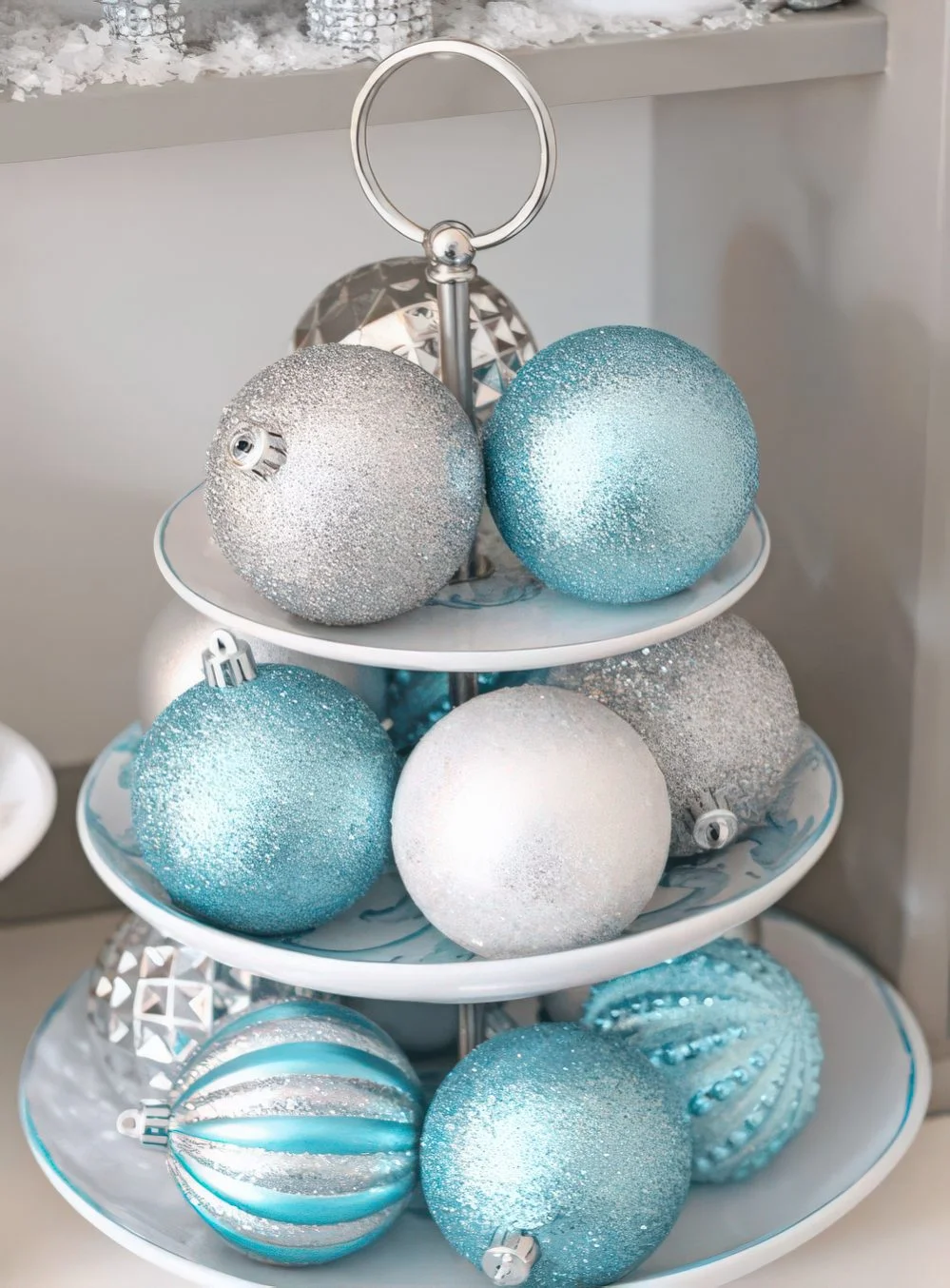 Gümüş ve mavi simli Noel süslerinin durduğu ayaklı stand, güzel bir merkez veya başka dekor.