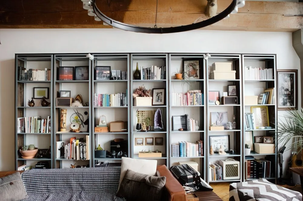 İçinde kitaplar, sanat eserleri ve dekoratif kaseler bulunan tam bir IKEA Hyllis raf kütüphanesi.
