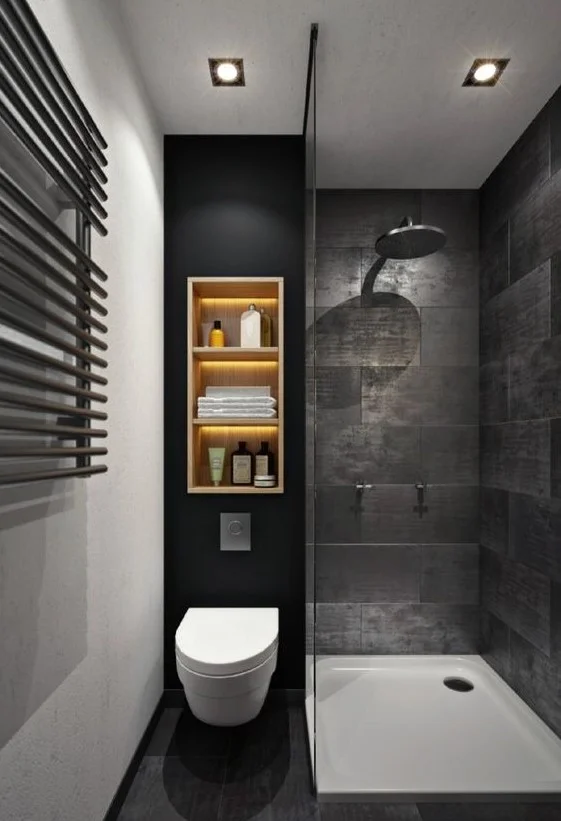 Taş desenli karolar, ışıklı duvar rafı ve duş alanı bulunan karanlık ve atmosferik siyah banyo.