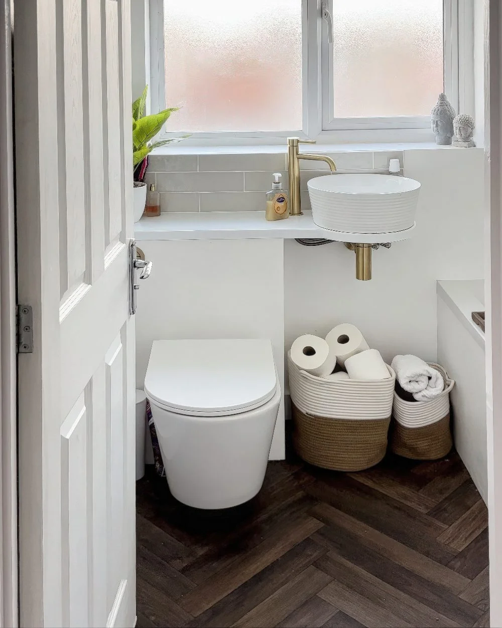 Bu modern küçük banyo, şık duvara monte tuvaleti, minimalist beyaz lavabo ve kompakt tezgahıyla alanı verimli kullanıyor. Pirinç musluk şıklık katıyor.