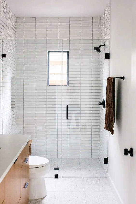 Nötr karolarla, ince ve desenli zemin, küçük pencere ve modern görünüm için siyah armatürlü küçük minimalist banyo.