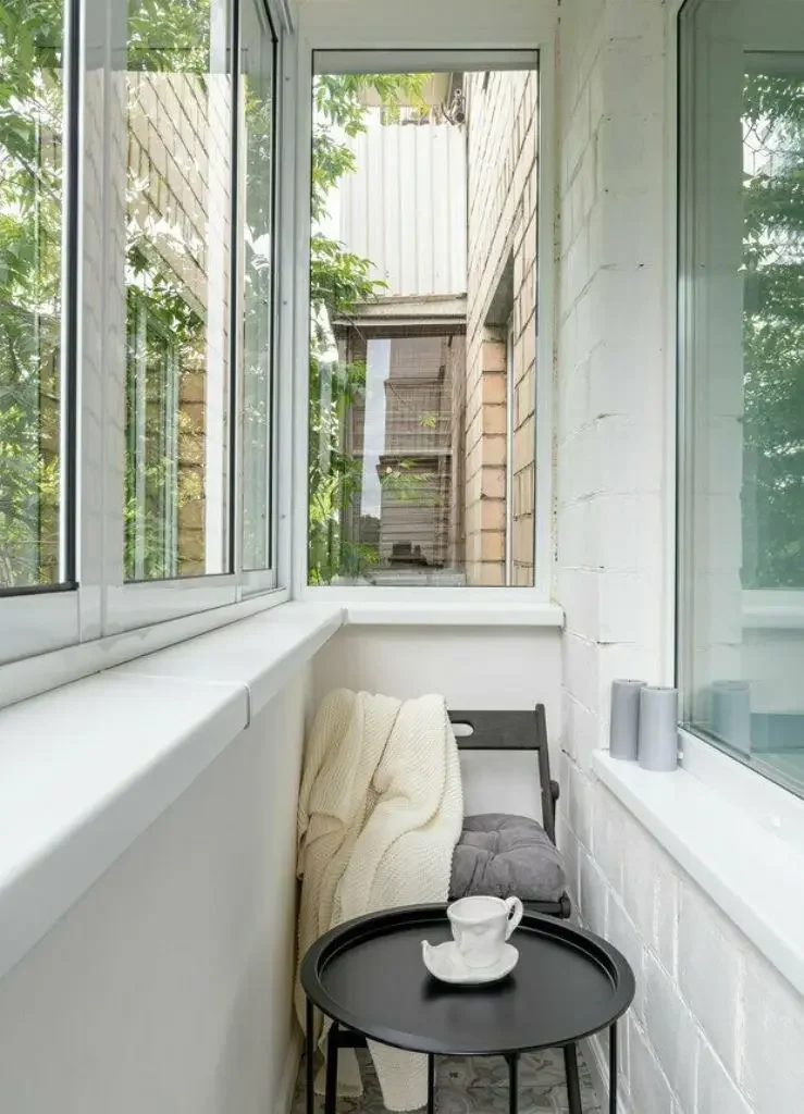 Bu dar kapalı balkon, koyu renk mobilyalar ve birkaç mumla dekore edilmiş, basit bir kahve köşesi.