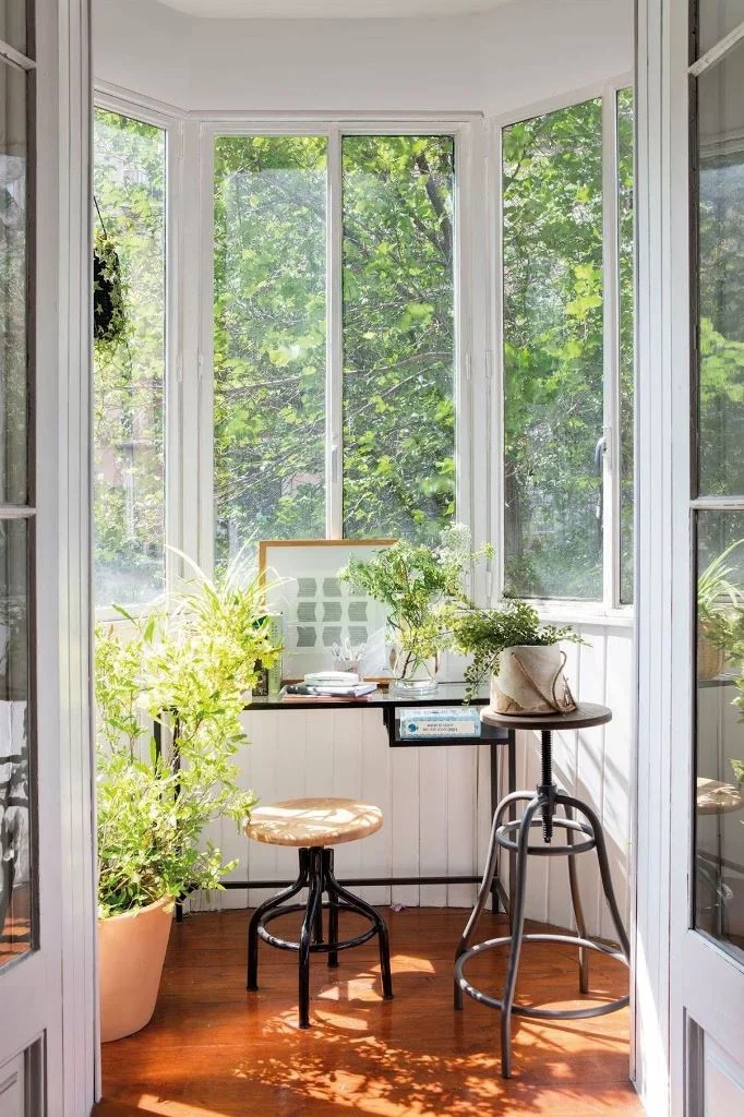 Bu küçük kapalı balkon, yeşillikler ve çiçeklerle mini bir çalışma alanına dönüşmüş.