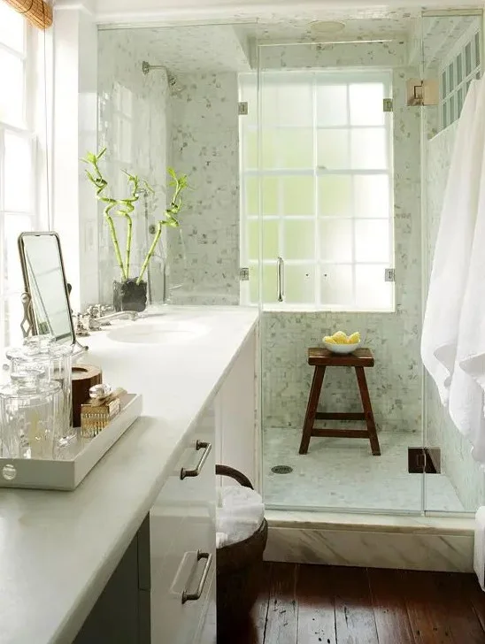 Sıcak küçük banyo; büyük lavabo, gömme lavabo, koyu renkli zemin ve açık yeşil duş alanı.