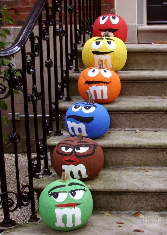 Renkli M&M şekerleriyle süslenmiş balkabakları, eğlenceli ve herkesin ilgisini çekecek bir fikirdir.