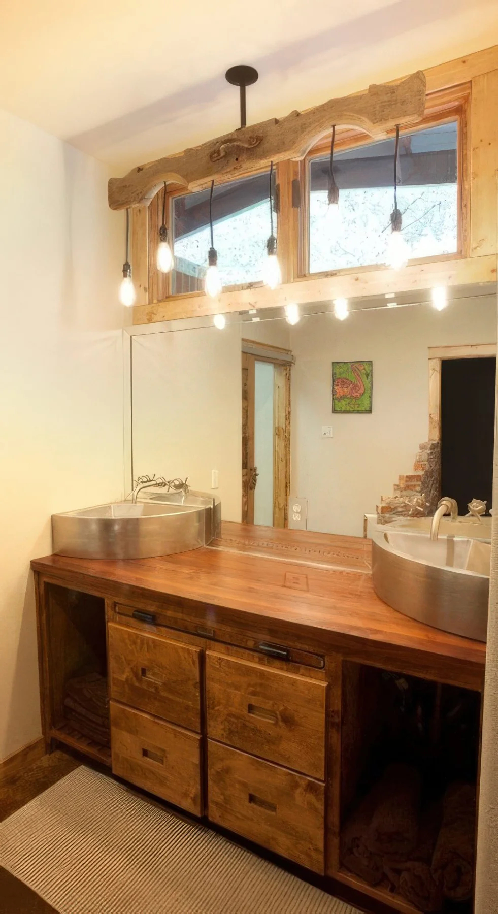 Rustik ahşap lavabo dolabı, ampullü dikkat çekici avize, metal lavabolar; serin ve samimi bir ahır banyosu.