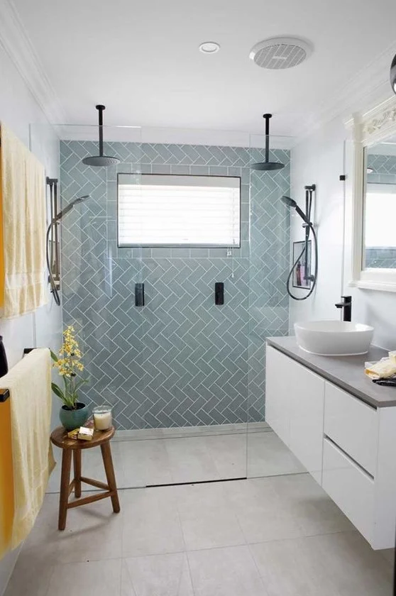 Şık küçük banyo; açık mavi karolar, beton tezgahlı asma beyaz lavabo, siyah armatürler ve cesur tekstiller.
