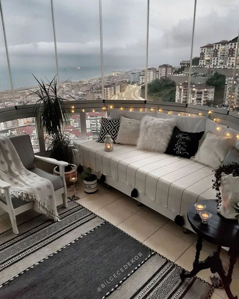 Kavisli balkon, şehir manzarası ve siyah-beyaz renk düzeniyle açık hava oturma odası gibi tasarlanmış.
