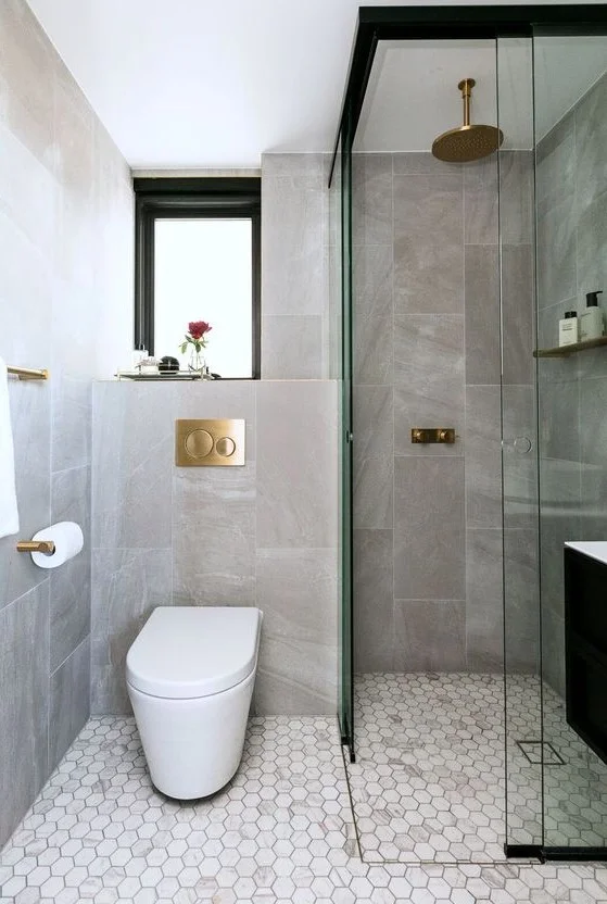 Taş ve mermer karolardan oluşan zarif çağdaş banyo, pencere, duş alanı ve altın detaylar içeriyor.