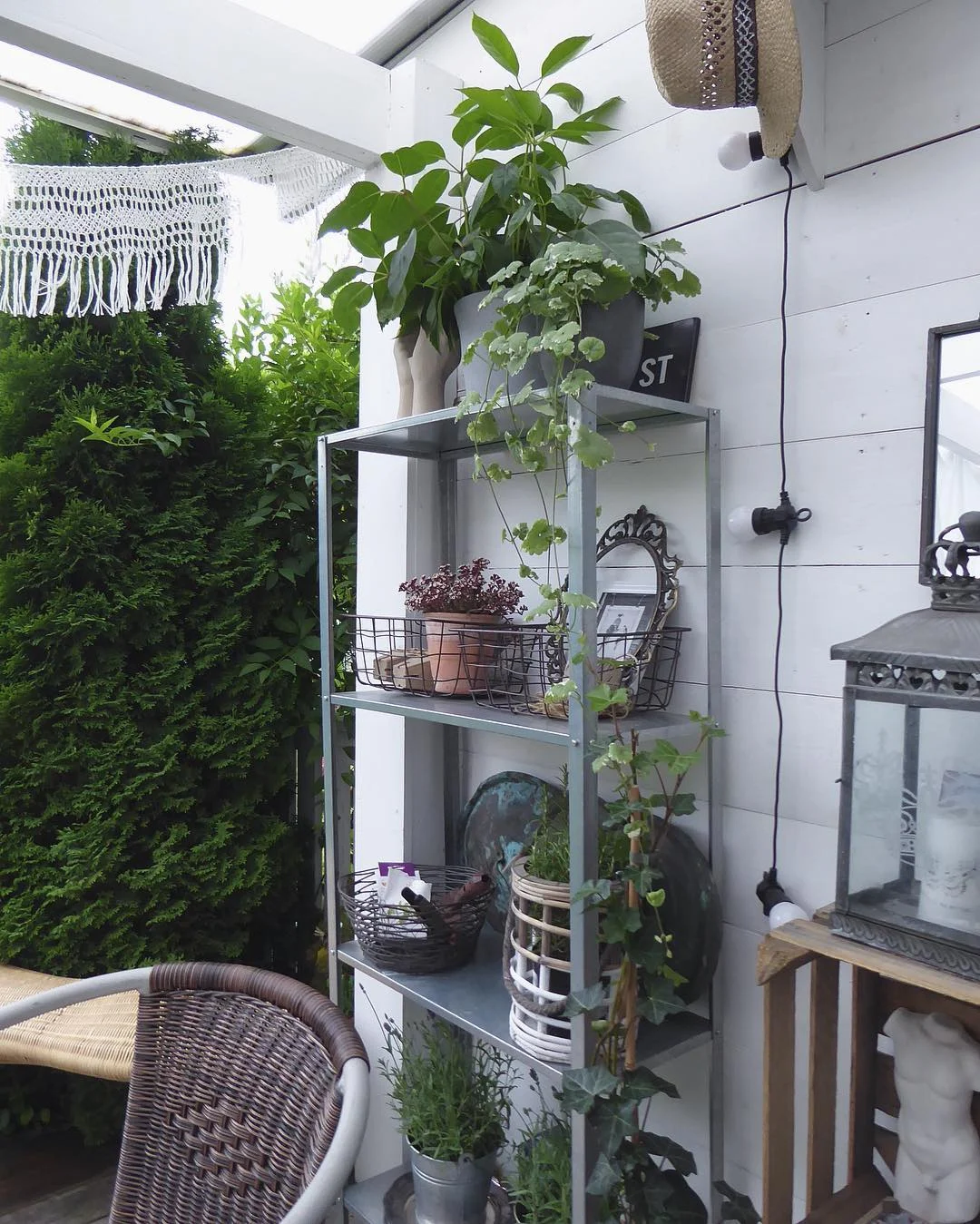 Galvanizli IKEA Hyllis, verandada saksı bitkileri ve sepetlerle dolu, doğayla uyumlu bir dış mekan köşesi oluşturmuş.