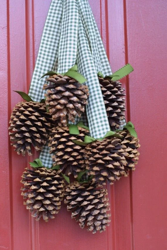 Gingham kurdelelerle asılan kozalaklardan yapılmış basit ve hızlı bir sonbahar kapı süsü.