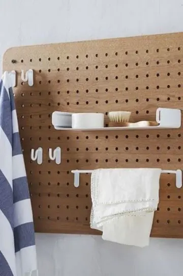 Ray, raf ve askılarla donatılmış boyalı pegboard, banyo için güzel bir depolama ve düzenleme çözümü.