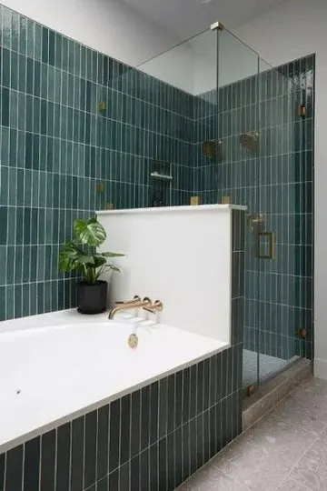 Yeşil ince fayanslı güzel banyo, küvet ile duşu ayıran alçak duvar harika görünüyor.