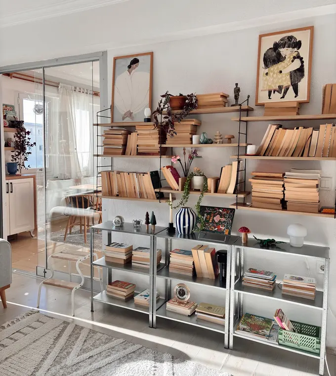 IKEA Hyllis rafları kitaplarla dolu, vazolar ve sanat eserleriyle şık bir depolama duvarı oluşturuyor.