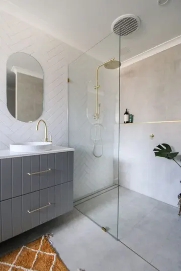 Gri beton ve beyaz kılçık karolar, gri lavabo, altın armatürler ile modern ve şık küçük banyo.