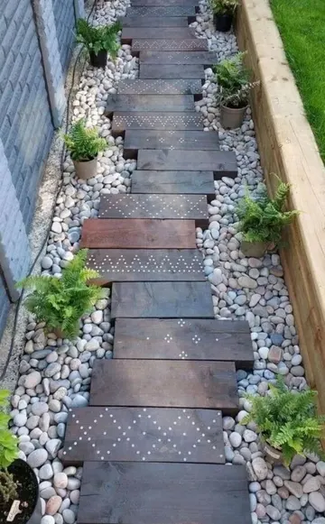 Güzel yol çakıl, renklendirilmiş geri kazanılmış ahşap ve saksıdaki eğrelti otu ile oluşturulmuş.