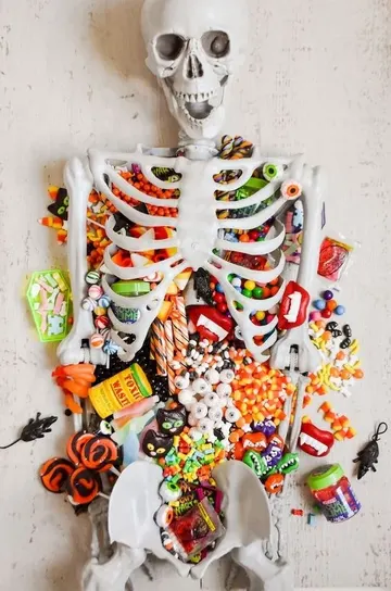 İskeletle süslenmiş şeker masası, misafirlere tatlı sunmanın harika Cadılar Bayramı çözümü.