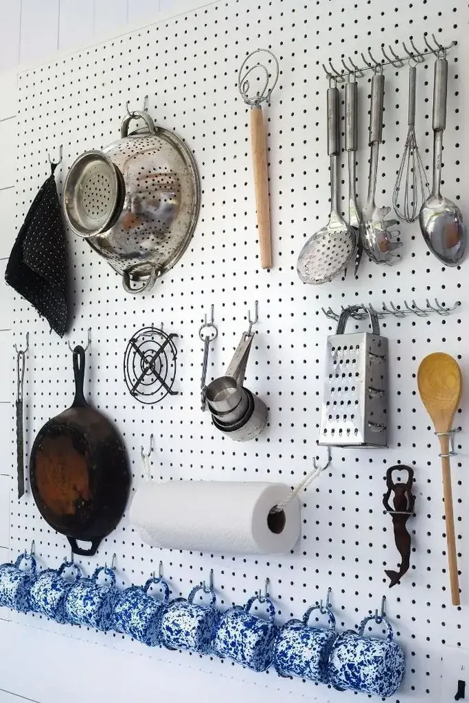 Büyük beyaz pegboard, ihtiyacınız olan tüm kanca ve askıları tutuyor.