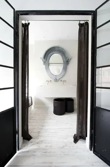 Nötr tonlarda eklektik stil, geniş duvara monte lavabo ve patina çerçeveli aynası bulunan misafir tuvaleti.