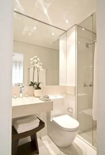 Büyük ayna, kare lavabo, duş alanı ve koyu lekeli ahşap tabureli nötr minimal banyo.