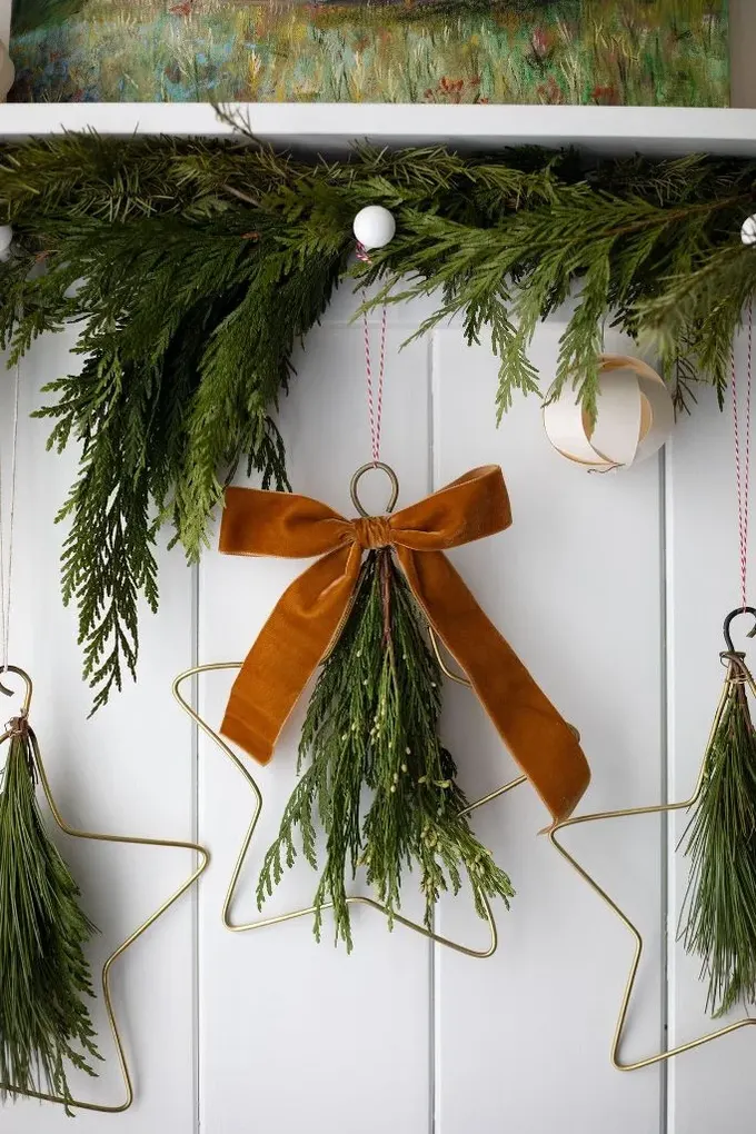 Yıldız şeklinde çerçeveli süsler, daimi yeşillikler ve pas sarısı kadife fiyonklar evinizi Noel için harika stilize eder.