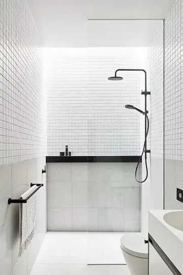 Beyaz küçük ve büyük karolar, siyah armatürler ve siyah-beyaz minimalist küçük banyo.