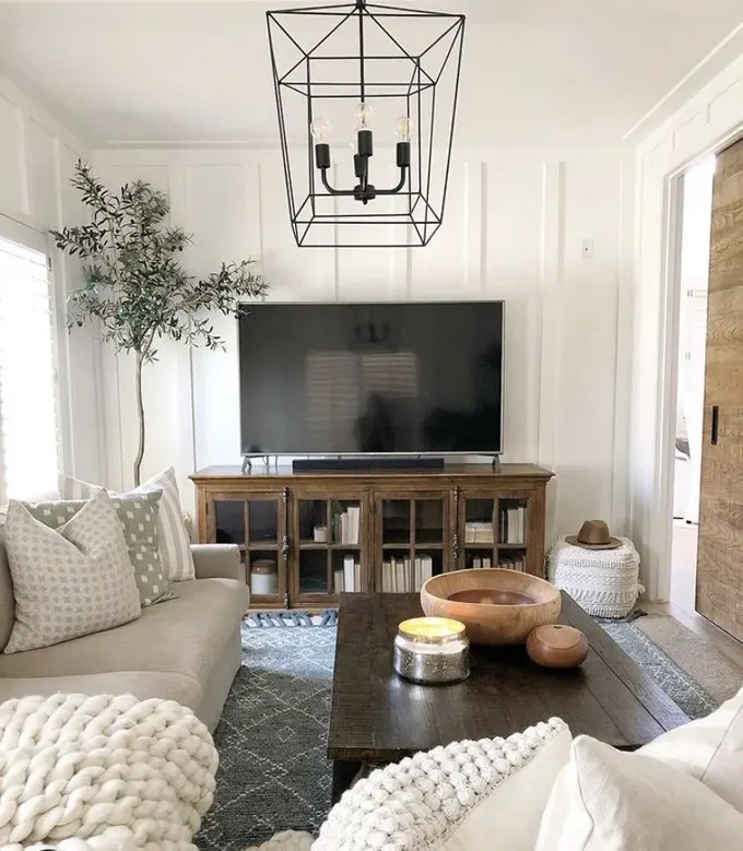 Bu çiftlik stili oturma odası akıllıca döşenmiş: L şeklinde bir kanepe, sehpa ve TV konsolu bulunuyor.