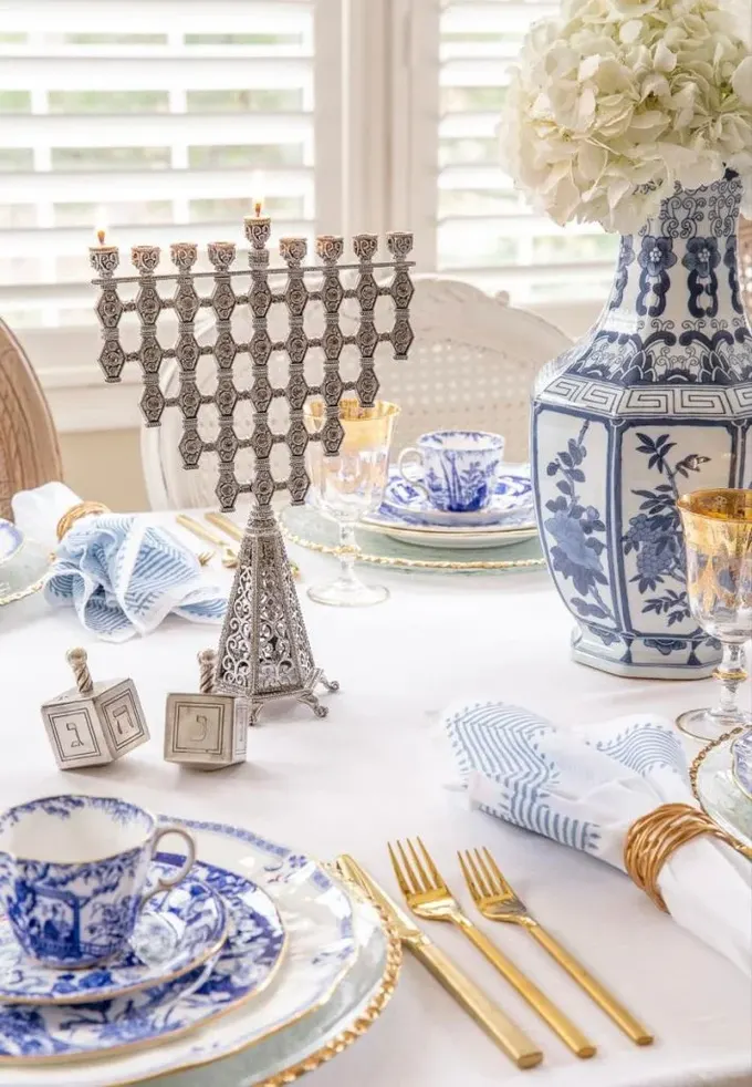 Şık menorah, masadaki zarif desenli porselan ile uyum içinde; çay masası düzeni için güzel bir örnek.