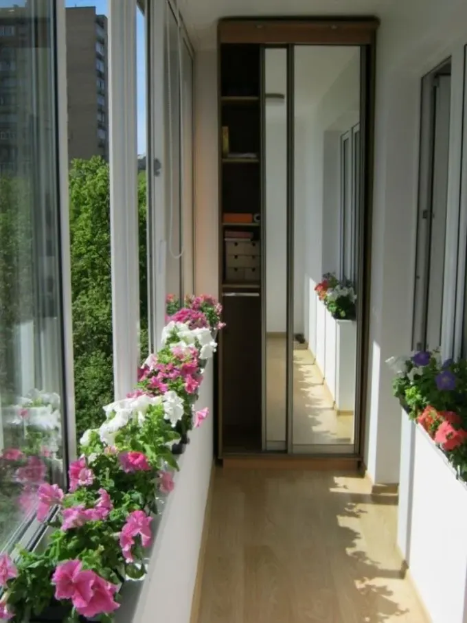 Uzun ve dar balkon renkli çiçeklerle dekore edilmiştir ve burada gömme depolama birimi bulunur.