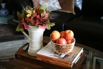 Elma dolu kase ve parlak sonbahar yapraklı sürahi, doğal ve hoş sonbahar sehpa dekoru.