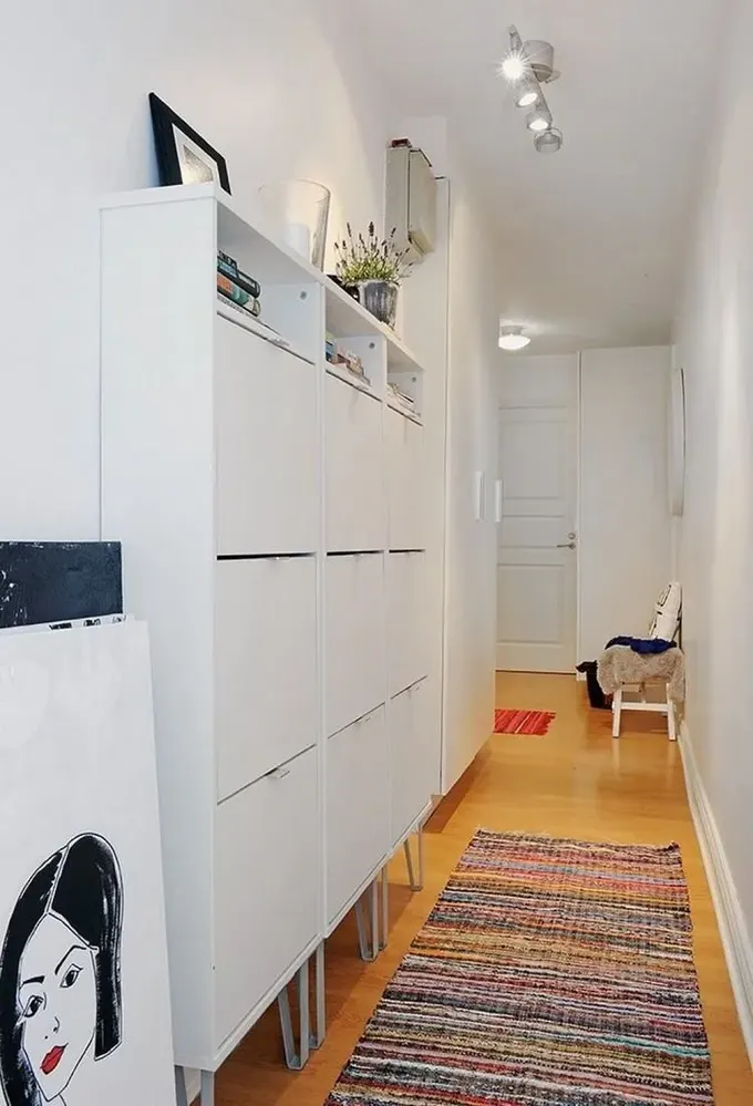 Her iki taraftaki açık beyaz raflar ve şık dolaplar geçişi engellemeden depolama sağlar.