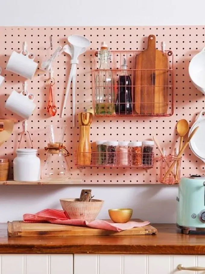 Pastel dokunuşlu mutfak için pegboard pembe boyanabilir, gül altın veya bakır tutucular eklenebilir.