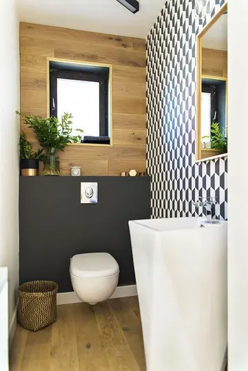 Geometrik duvar, kontrast siyah detay, serbest ayaklı lavabo ve kumaş sepetle şık misafir tuvaleti.