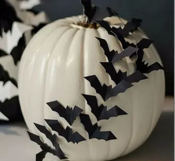 Siyah kağıt yarasalarla süslenmiş beyaz balkabağı, şık bir Halloween fikri ve yapımı çok kolay.