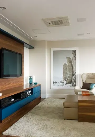 Duvara monte TV, sahte ahşap duvar ve medya konsolu ile nötr renklerde modern oturma odası.