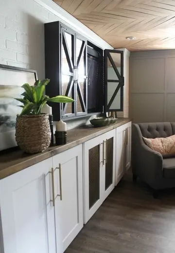 Beyaz dolaplar, kesim tablası tezgahlar, panjurlu kapakların arkasında TV ve modern mobilyalarla tasarlanmış modern oturma odası.
