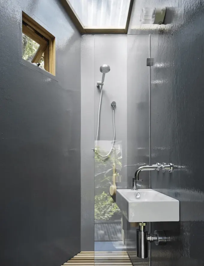 Üçgen şekilli banyo çok sade, duş alanı en küçük köşeye konumlandırılmış.