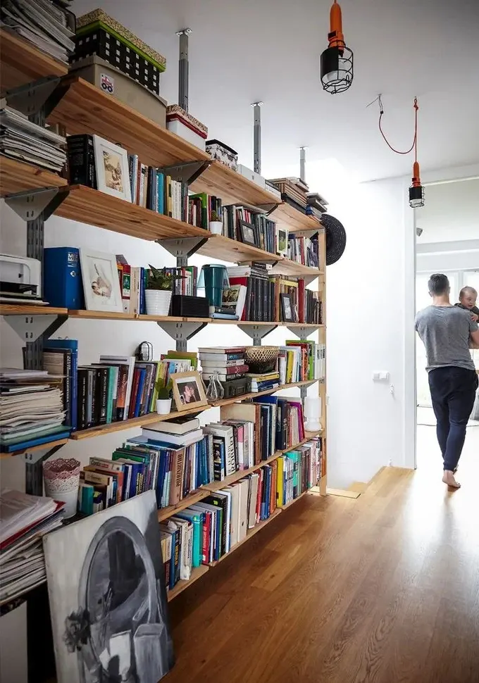 Kitap ve sanat eserleriyle dolu büyük açık raf ünitesi, koridor için mükemmel bir fikir; diğer odalarda depolama ihtiyacını azaltır.