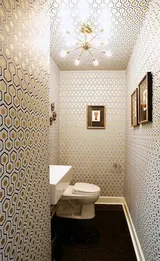 Geometrik duvar kağıdı, kare lavabo ve güneş şeklinde avizesiyle şık orta yüzyıl modern tuvalet.