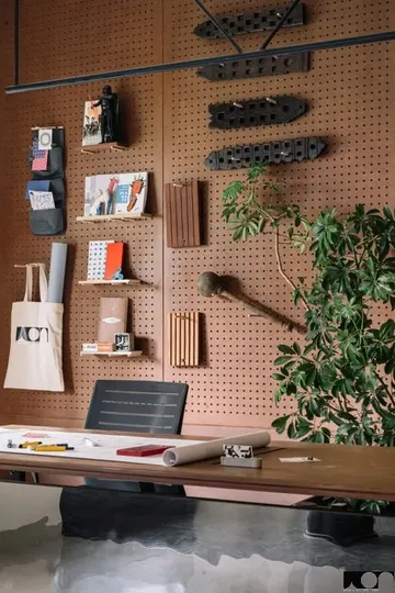 Paslı pegboard panelleri tüm masanın arkasındaki duvarı kaplayarak mekana renk ve atmosfer katıyor.