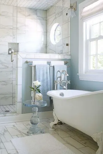 Mavi duvarlı güzel banyo, mermer kaplı duş alanı, vintage küvet ve duşta alçak duvar.