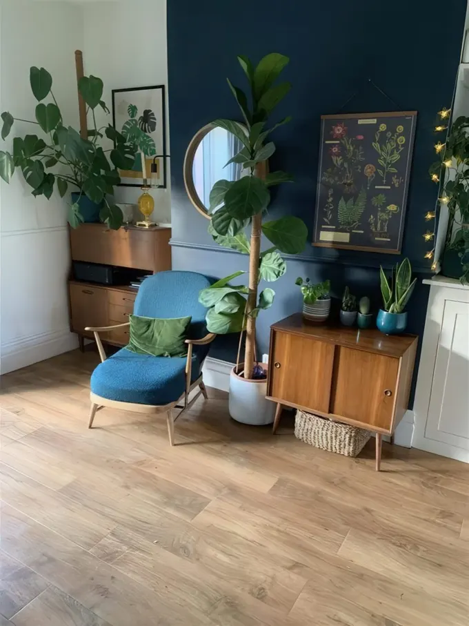 Bu köşe lacivert vurgu duvarı, aydınlatmalar, sanat eserleri, saksı bitkiler, lacivert sandalye, sepet ve orta yüzyıl modern depolama mobilyasıyla düzenlenmiş.